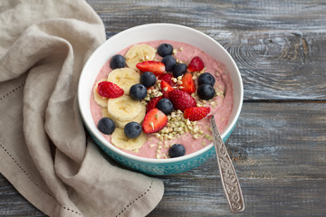 Healthy raw breakfast: porridge of sprouted green buckwheat with strawberries, blueberries and bananas on a wooden table
