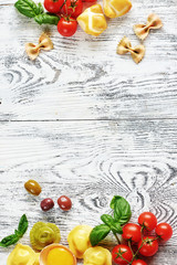 Italian kitchen background. Healthy ingredients for cooking: raw egg, tortellini, pasta, cheese, fresh tomato and basil on white wooden table with copy space.