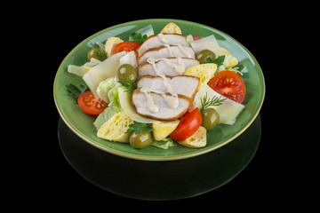 Ceasar salad with fresh vegetables and chiken. On a black background with reflection