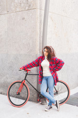 Fototapeta na wymiar Young beautiful mixed race woman listening music with headphones leaning on her bicycle - sportive, music concept
