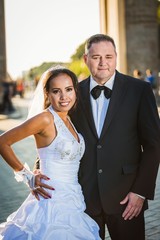 Portrait of a happy multicultural wedding couple at Brandenburger Gate with back sun light. Newlyweds. The two married are looking at the camera. © arianarama