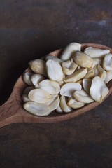 Peeled roasted peanuts in a wooden spoon on a rusty background.