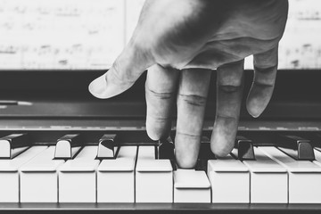 male musician hands playing on piano keys, black and white