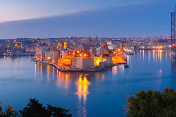 Fototapeta premium Skyline aerial view of ancient Fort Saint Michael of Senglea peninsula and the Grand Harbor as seen from Valletta during morning blue hour, Malta.