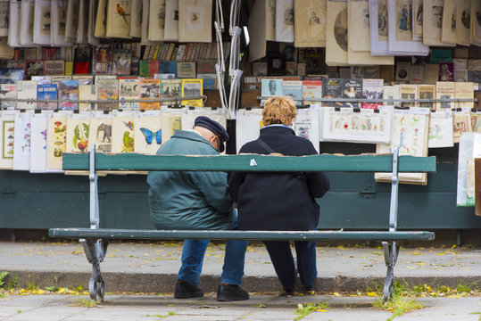 Fototapeta People on a bench at a second-hand book market on quay of river Seine near cathedral Notre Dame in Paris