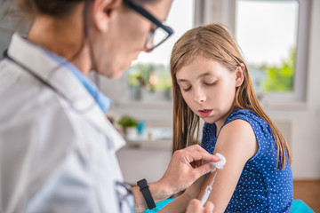 Doctor giving a young girl a vaccine shot