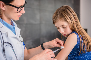 Doctor giving a young girl a vaccine shot