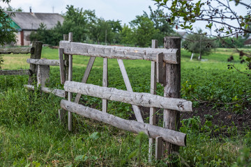 Fototapeta na wymiar Wooden fence fields in a village in the summer overcast