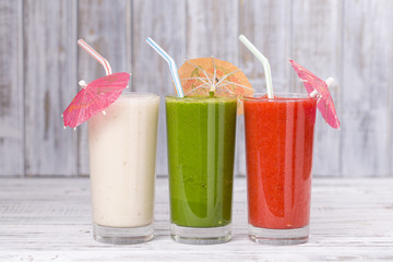 Fresh avocado, strawberry and banana drinks on wooden table, assorted protein cocktails with fresh fruits.