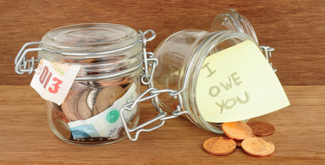 Glass jars filled with cash savings on a wood background © philip kinsey