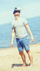 man in a VR glasses operating in virtual reality sandy beach, geting a new experience  using 360 Degrees Headset.