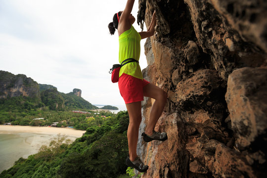 woman rock climber climbing at seaside cliff