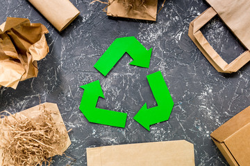 Paper recycle sign with paper and carton garbage on grey table background top view