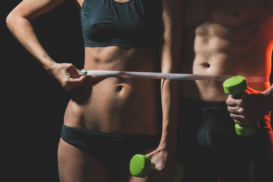 couple of sexy woman and athletic man with dumbbell
