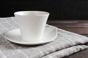 White cup and tablecloth on a dark wooden table