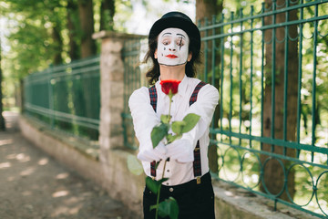 Emotional male mime artist with red rose performing love on a outdoor.