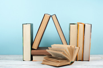 Open book, hardback colorful books on wooden table, blue background. Back to school. Copy space for...