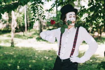 Emotional male mime artist with red rose performing love on a outdoor.