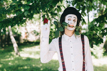Emotional male mime artist with red rose performing love on a outdoor.
