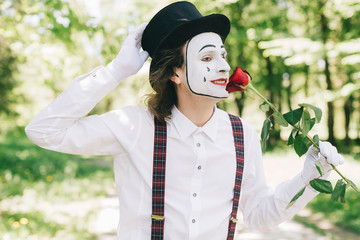 Emotional male mime artist with red rose performing love on a outdoor.