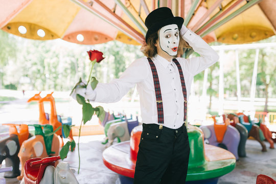A funny pantomime from a circus rides a swing.
