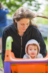 Emotional portrait of a mother playing with her infant daughter on a small plastic slide