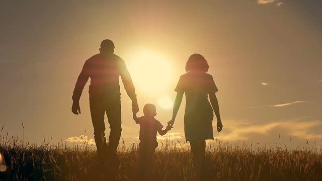 Happy young family with children running around the field, silhouette at sunset