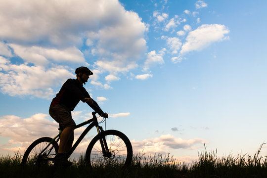 Mountain biker cycling silhouette over blue sky