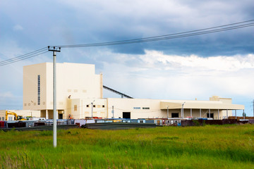A small factory in the background of a cloudy sky. View from outside