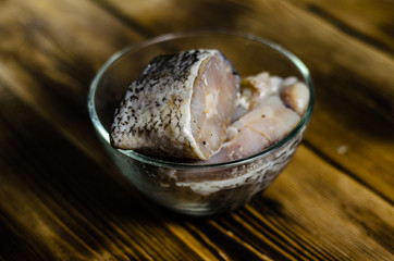 Pieces of the marinated carp in bowl on wooden table