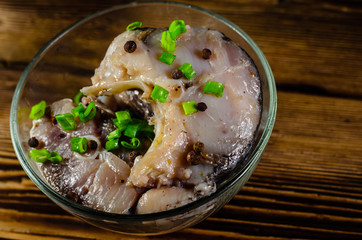 Pieces of the marinated carp in bowl on wooden table