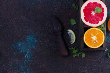 Fototapeta na wymiar Orange, lemon and grapefruit and citrus reamer with copy space on dark background