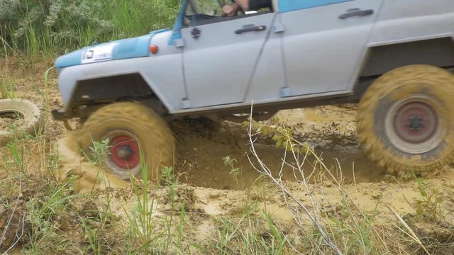 Car wheel on a dirt road. Off-road tire covered with mud, dirt terrain. Outdoor, adventures and travel suv. Car tire close-up in a countryside landscape with a muddy road. Four wheel truck in mud.