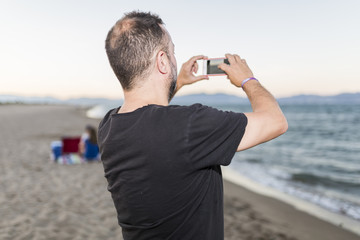  man on the beach taking photos with mobile