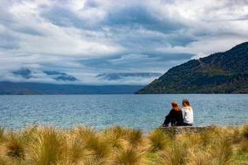 girls sitting on lake edge