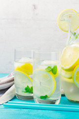 Lemonade homemade drink - two glasses and jar close up with ice and mint