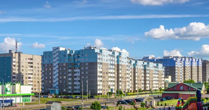 Time lapse clip of white fluffy rolling clouds against the background of apartment buildings