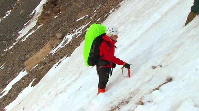 Climbers with large backpack using an ice ax goes on a snowy ridge
