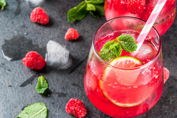 Summer refreshing non-alcoholic cocktails. Fruit drinks. Raspberry mojito lemonade with fresh organic mint and lime. On a black stone table. Copy space