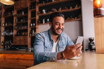 Man having video chat on smart phone at cafe - obrazy, fototapety, plakaty