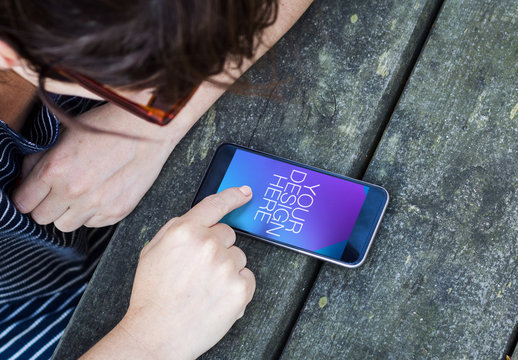 User Tapping Smartphone at Wooden Table Mockup 1