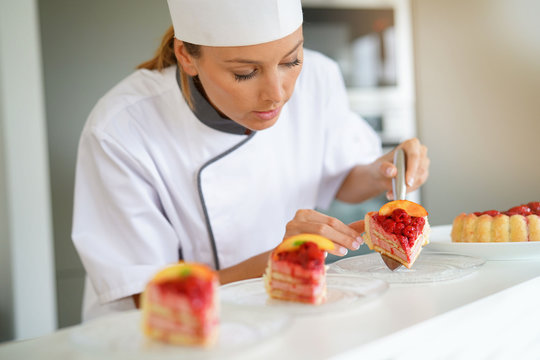 Portrait of pastry chef cutting slices of cake for serving