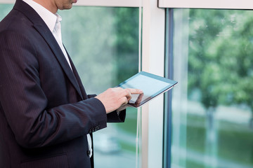 Close up image of business man holding a digital tablet,Portrait of handsome young man working with tablet in the office.Intelligent and confidents businessman holding touch pad with infographics
