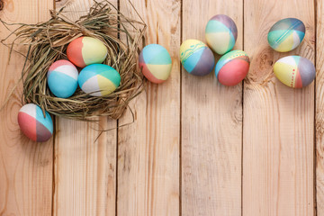 Easter eggs in straw nest on a light wooden background