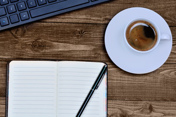 Keyboard computer with notepad and coffee on table