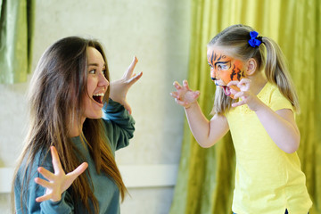 Adorable little girl painted like tiger playing with animator