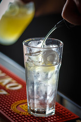 The barman pours cold drinks into a glass goblet