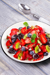 Strawberry, blackberry, blueberry and kiwi salad, garnished with mint. Fruit and berry salad
