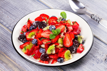 Strawberry, blackberry, blueberry and kiwi salad, garnished with mint. Fruit and berry salad