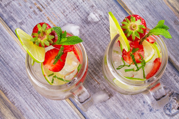 Strawberry mojito. Detox fruit and berry infused flavored water in jars. Refreshing summer homemade cocktail. View from above, top studio shot